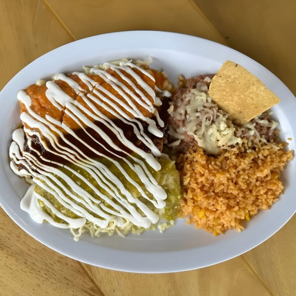 A plate of enchiladas with red, mole, and green sauces, served with rice and refried beans.