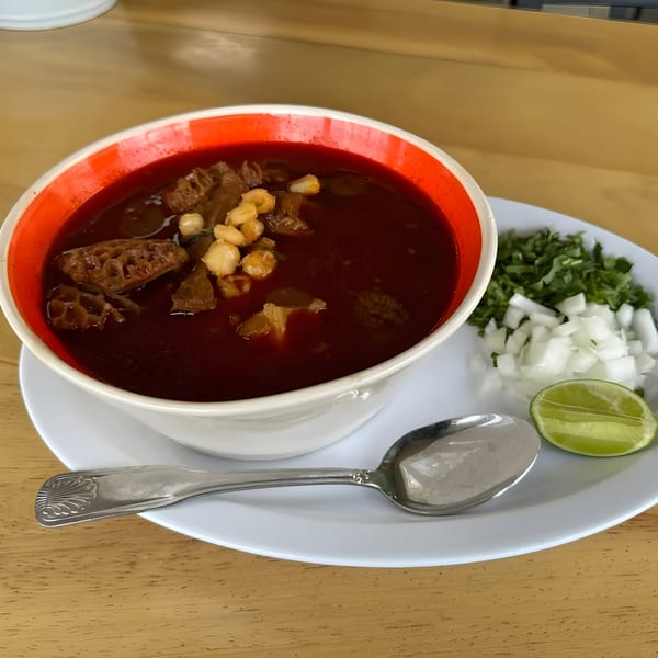 Menudo soup with tripe, hominy, and a side of chopped onions, cilantro, and lime.