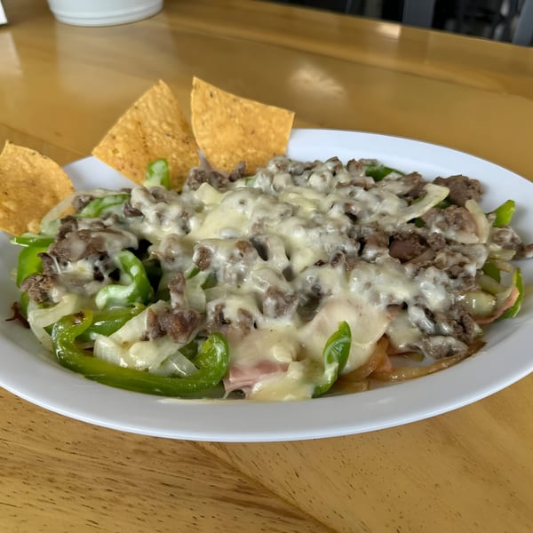 Mexican dish with melted cheese over beef, green peppers, onions, and tortilla chips.